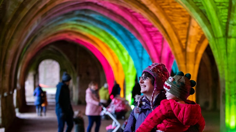 A mother with her baby enjoying the annual Music and Lights Christmas event at Fountains Abbey